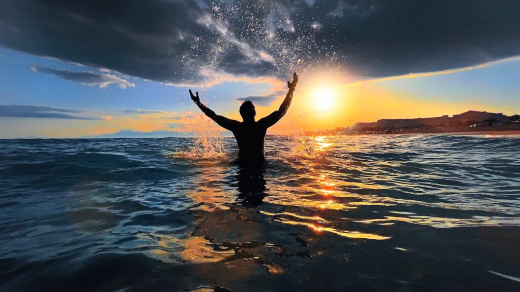 Silhouette of a person splashing water at sunset on a beach in Antalya, Turkey.